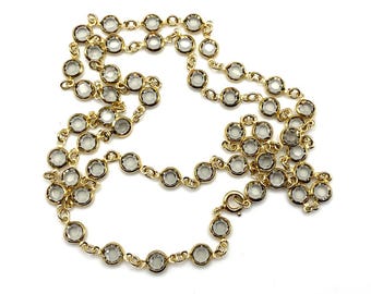 May include: A gold chain necklace with clear round stones. The necklace is made of small, linked chains with a round stone at each link.