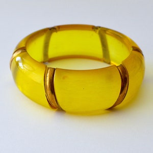 May include: A yellow plastic bangle bracelet with gold accents.