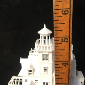 May include: White model of a haunted house with a tower, measuring approximately 5 inches tall. The model is made of plastic and has a detailed design.
