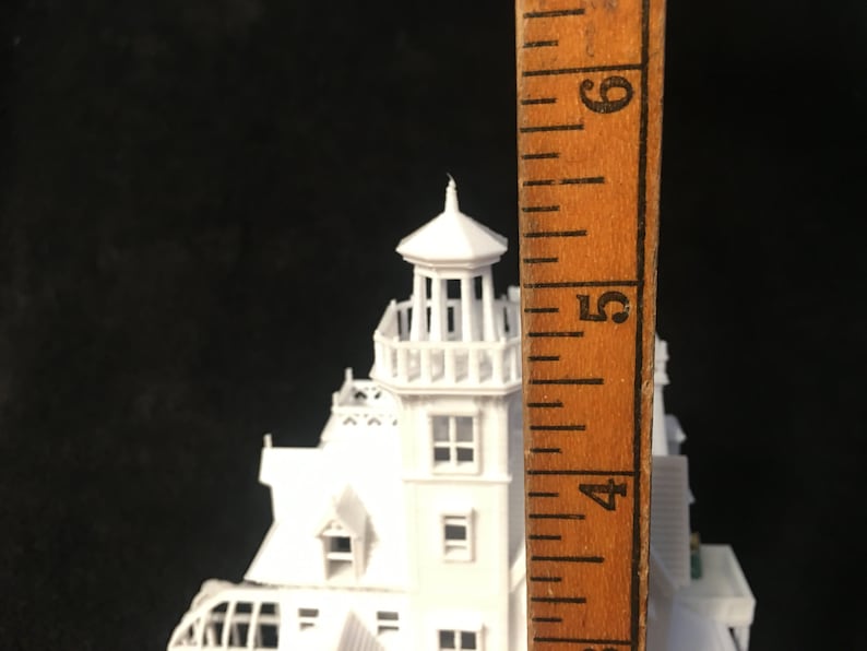May include: White model of a haunted house with a tower, measuring approximately 5 inches tall. The model is made of plastic and has a detailed design.