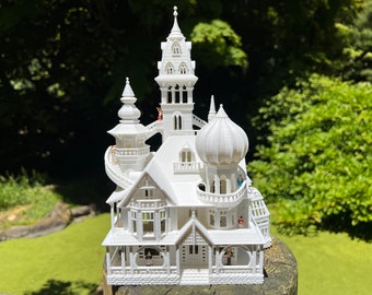 May include: A white 3D printed model of a whimsical, multi-level house with a spiral staircase and a domed roof. Tiny figures are placed on the balconies and stairs.
