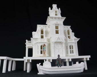 May include: A white 3D printed model of a Victorian house on stilts with a small boat in front of it. Two miniature figures stand in front of the house.