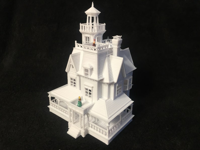 May include: A white 3D printed model of a Victorian style house with a tower and a porch. The model is detailed with windows, doors, and a roof.