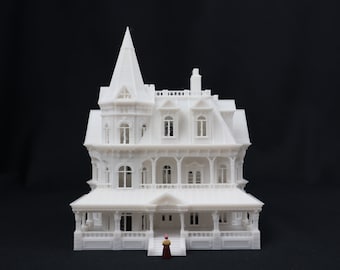 Könnte beinhalten: Ein weißes 3D-gedrucktes Modell eines Hauses im viktorianischen Stil mit einem hohen Turm und einer Veranda, die das Haus umläuft. Eine kleine Figur steht vor dem Haus.