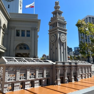 May include: A grey 3D printed model of the Ferry Building in San Francisco. The model includes the clock tower and the main building with a glass roof.