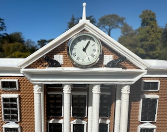 May include: A white model of a building with a clock tower. The clock face has black Roman numerals and hands. There are two black cat figurines on the roof.