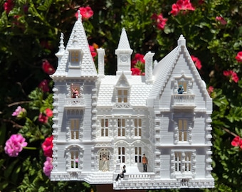 May include: A white 3D printed model of a large, detailed Victorian mansion with several windows and a clock tower.  The model is set against a backdrop of green foliage with pink flowers.
