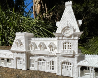 May include: A white 3D printed model of a train station with a clock tower and a detailed facade.