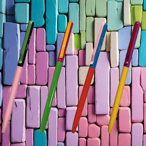 May include: Four colorful pens with different colored caps and bodies. The pens are arranged in a diagonal line against a background of pastel colored blocks.