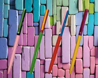 Può includere: Quattro penne colorate con tappi e corpi di diversi colori. Le penne sono disposte in diagonale su uno sfondo di blocchi color pastello.