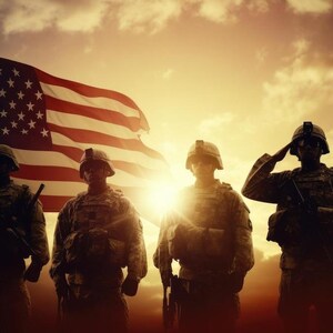 May include: Silhouettes of four soldiers standing in front of an American flag waving in the wind. The soldiers are wearing military uniforms and holding rifles. The sky is a vibrant orange and yellow, suggesting a sunset.