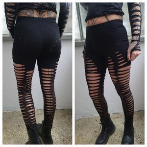 Könnte beinhalten: Schwarze Leggings mit mehreren vertikalen Schlitzen über die gesamte Länge der Beine. Die Leggings sind aus dehnbarem Stoff und haben einen hohen Bund.