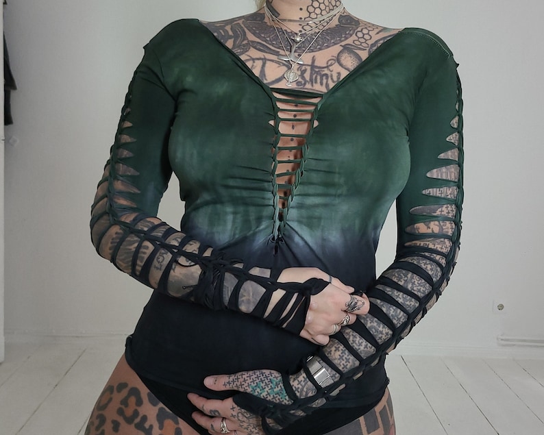 Pu&ograve; includere: Una camicia a maniche lunghe con un design sfumato verde e nero. La camicia ha una scollatura a V profonda ed &egrave; realizzata in un tessuto morbido ed elastico. Le maniche hanno un design unico con tagli.