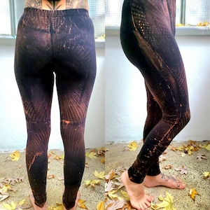 Puede incluir: Leggings negros con un patrón de tie-dye marrón y naranja. Los leggings son ajustados y tienen una cintura alta.