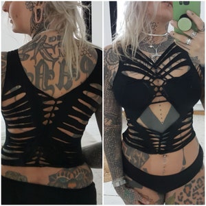 Könnte beinhalten: Schwarzes Crop-Top mit Kreuzdesign auf dem Rücken und Cut-Out-Design auf der Vorderseite. Das Top ist aus dehnbarem Stoff und hat eine figurbetonte Silhouette.