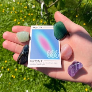 May include: A card with the number 888 and the word "INFINITY" printed on it. The card is surrounded by six different colored gemstones: green, light green, black, pink, purple, and a light blue gemstone.