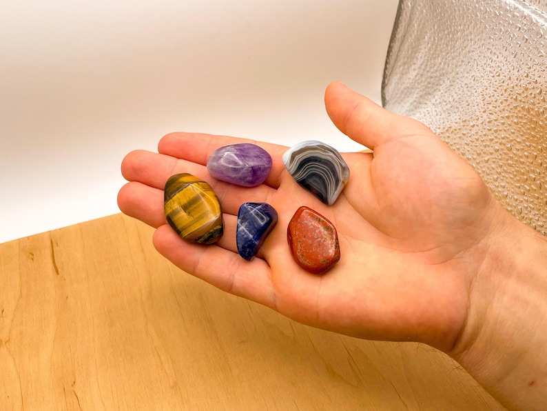 Peut inclure: Une collection de six pierres roul&eacute;es de diff&eacute;rentes couleurs, dont l'am&eacute;thyste violette, le lapis-lazuli bleu, l'&oelig;il de tigre brun, le jaspe rouge et l'agate grise.