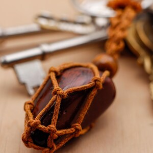 May include: A brown wooden charm wrapped in brown twine, attached to a set of keys. The charm is shaped like a small bottle and has a brown wooden stopper.