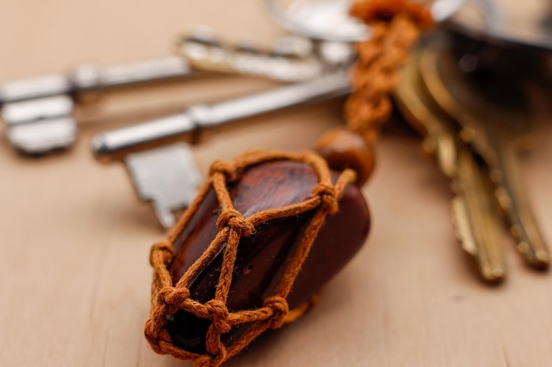 May include: A brown wooden charm wrapped in brown twine, attached to a set of keys. The charm is shaped like a small bottle and has a brown wooden stopper.
