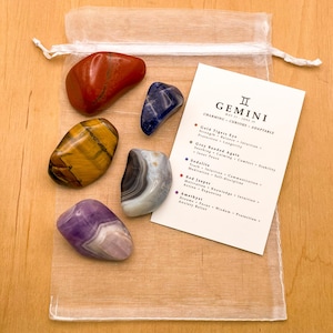Peut inclure: Un ensemble de six pierres roul&eacute;es dans un sac en organza blanc avec une carte qui indique "G&eacute;meaux : Charmant - Curieux - Adaptable" et liste les pierres et leurs significations associ&eacute;es. Les pierres sont du jaspe rouge, de l'&oelig;il de tigre dor&eacute;, de l'agate ruban&eacute;e grise, de la sodalite, de l'am&eacute;thyste et de l'agate bleue.
