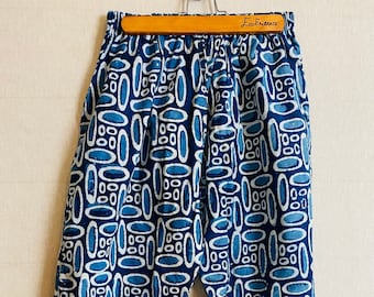 May include: Blue and white patterned pants with an elastic waistband. The pants have a geometric pattern of ovals and circles.