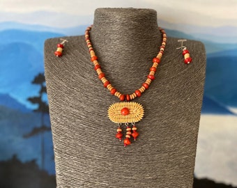 May include: A necklace and earrings set made of natural wood beads in shades of brown and red. The necklace features a woven pendant with a red bead accent.