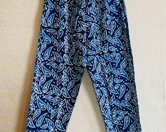 May include: Blue and white patterned pants hanging on a wooden hanger. The pants feature a repeating paisley-like design in shades of blue and white. The pants have an elastic waistband. The hanger has the word "Ecobreeze" written on it.