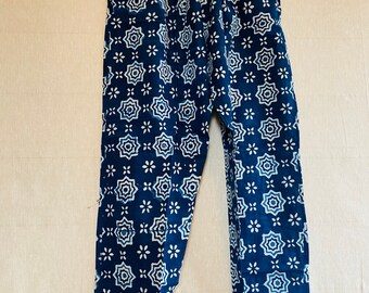 May include: Blue cotton pants with a white geometric pattern. The pants have an elastic waistband and a relaxed fit.