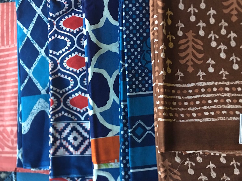 May include: A collection of six fabric swatches featuring a variety of blue and white patterns, including geometric designs, polka dots, and floral motifs. One swatch is brown with a white floral pattern.