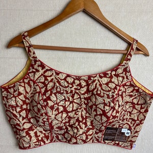 May include: A red and cream printed cotton blouse with a scoop neck and spaghetti straps. The blouse has a size tag that says "M".