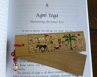 May include: A book with a brown bookmark featuring a colourful illustration of people and animals. The book's title is "Agni Yoga: Harnessing the Inner Fire". The text on the bookmark reads "He has no disease, nor old age, nor death, who has attained..."