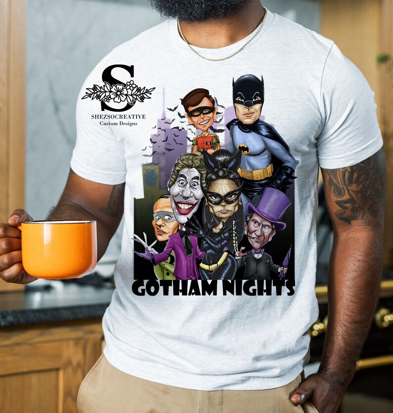 May include: White t-shirt with a graphic print of Batman, Robin, Joker, Catwoman, and The Penguin. The graphic is in a cartoon style and features the text "Gotham Nights".