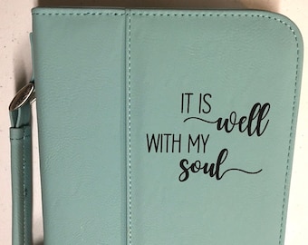 Op de afbeelding: Een lichtblauwe kunstleren Bijbelhoes met de tekst "It is well with my soul" en de naam "Amanda Maria Cole" gedrukt op de voorkant.