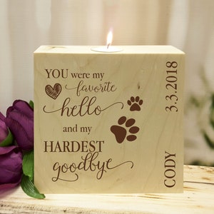 May include: Wooden candle holder with the text "You were my favorite hello and my hardest goodbye" with paw prints and a heart. The date "3.3.2018" and the name "Cody" are also engraved on the holder.
