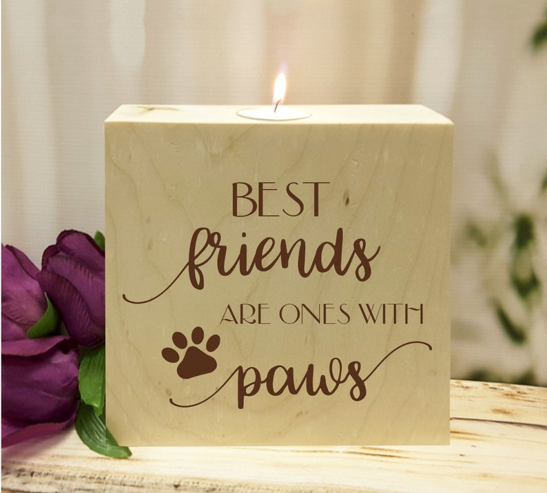 May include: Wooden candle holder with the text "Best friends are ones with paws" and a paw print. The candle holder is light brown and has a small tea light candle in the center.