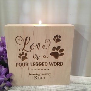 May include: Wooden candle holder with the text "Love is a four legged word" and paw prints. The text "In loving memory Kody" is also engraved on the holder.