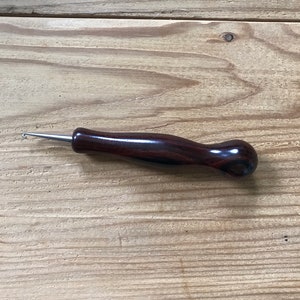 May include: A wooden crochet hook with a dark brown handle and a silver hook.