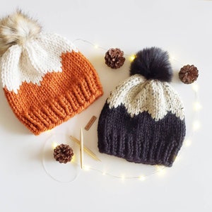 Peut inclure: Deux bonnets en tricot avec des blocs de couleurs contrastées et des pompons en fausse fourrure. Le bonnet de gauche est blanc et orange, tandis que le bonnet de droite est blanc et noir.