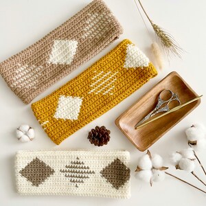 Pode incluir: Tr&ecirc;s faixas de cabe&ccedil;a de croch&ecirc; em diferentes cores e padr&otilde;es. As faixas de cabe&ccedil;a s&atilde;o feitas com fio branco, marrom e amarelo. As faixas de cabe&ccedil;a est&atilde;o dispostas em uma superf&iacute;cie branca com bolas de algod&atilde;o e uma bandeja de madeira com tesoura.
