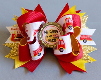 May include: Red, yellow, and gold bow with a white ribbon featuring a fire truck and the text "My Daddy is My Hero".