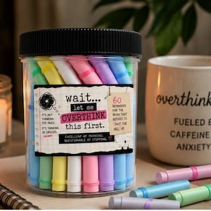 May include: A clear plastic jar with a black lid containing 60 pastel-colored paper scrolls. The label reads: wait... let me OVERTHINK THIS FIRST. It's not thinking too much, it's thinking in circles. 60 reminders for the brain that refuses to shut the hell up. Excellent at thinking, questionable at stopping.