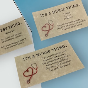 May include: Three rectangular cards with a tan, textured background featuring black printed text and a red stethoscope shaped like a heart. The text includes phrases such as IT'S A NURSE THING, Nurse life, and various humorous quotes about nursing.