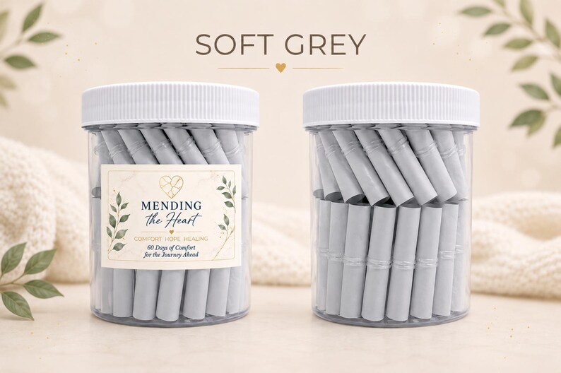 May include: Two clear plastic jars with white lids, each filled with rolled-up light grey paper slips. The left jar features a label reading MENDING the Heart COMFORT HOPE HEALING 60 Days of Comfort for the Journey Ahead with leaf graphics.