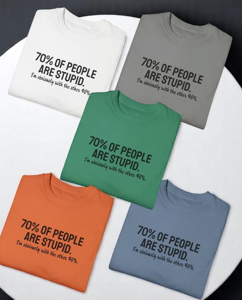 May include: Five crew neck t-shirts in white, gray, green, orange, and blue. Each shirt features the black printed text: 70% OF PEOPLE ARE STUPID. I'm obviously with the other 40%. The shirts are arranged in a circular pattern on a white surface.