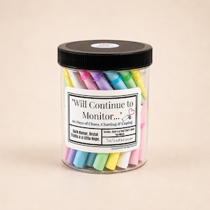 May include: A clear plastic jar with a black lid filled with colorful rolled paper notes. The label reads: Will Continue to Monitor... 60 Days of Chaos, Charting & Coping. Dark Humor, Brutal Truths & a Little Hope. Scrubs, Sass & a Soul That's Seen Too Much.
