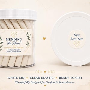 May include: A clear plastic jar with a white lid containing rolled paper slips. The label reads MENDING the Heart, COMFORT HOPE HEALING, 60 Days of Comfort for the Journey Ahead. The lid features a sticker with the text hope lives here.