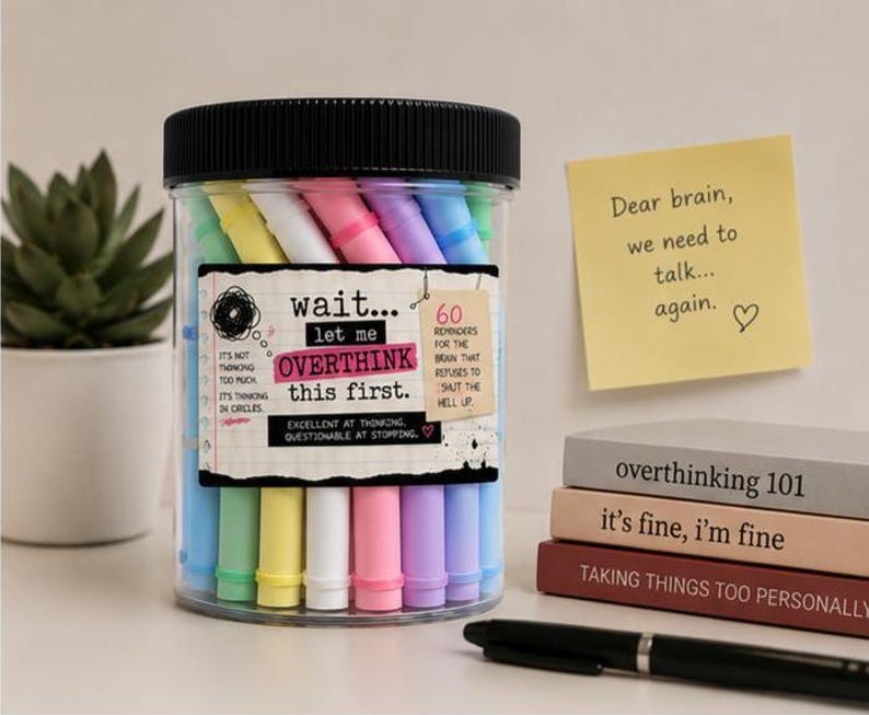May include: A clear plastic jar with a black lid filled with pastel-colored markers. The label reads: wait... let me OVERTHINK this first. It's not thinking too much. It's thinking in circles. 60 reminders for the brain that refuses to shut the hell up.