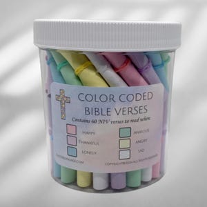 May include: A clear plastic container filled with colorful, rolled paper scrolls. The label reads "COLOR CODED BIBLE VERSES" and lists emotions like "HAPPY" and "ANXIOUS." The container has a white lid.