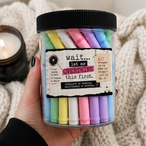 May include: A clear plastic jar with a black lid containing pastel-colored markers. The label reads: wait... let me OVERTHINK this first. 60 REMINDERS FOR THE BRAIN THAT REFUSES TO SHUT THE HELL UP. IT'S NOT THINKING TOO MUCH, IT'S THINKING IN CIRCLES.