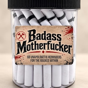 May include: A clear plastic jar with a black screw-top lid filled with white paper scrolls secured by black rubber bands. The label features the text Badass Motherfucker 60 UNAPOLOGETIC REMINDERS FOR THE BADASS WITHIN in black font.